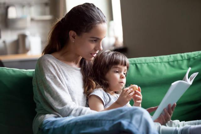 Young mother reading to daughter on the couch